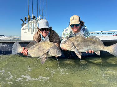 DMFD Life charter captains holding large fish on a boat with a clear blue sky wearing Deer Meat For Dinner hats