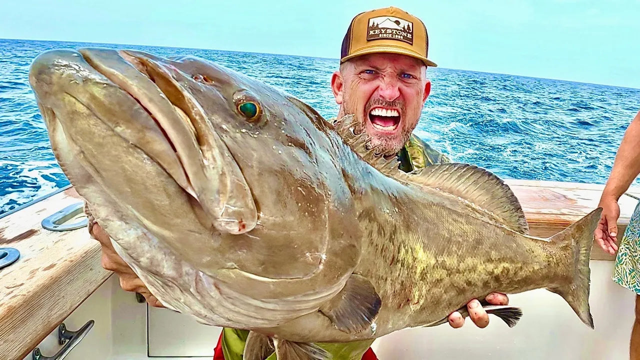 Robert Arrington  holding a large fish on a boat with ocean in the background